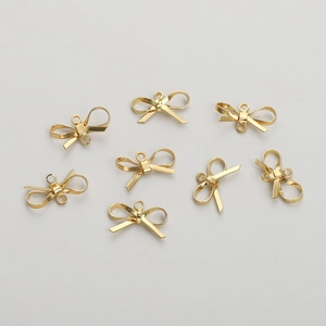 Detail of 14K gold-plated bow pendants for jewelry making shown on a white background