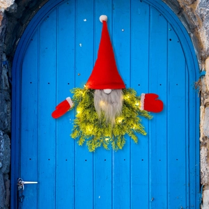 Lighted Christmas gnome wreath with red hat and LED lights hanging on a blue door