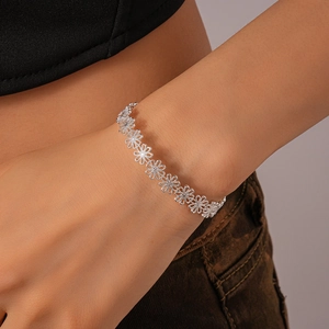 Detail shot of silver daisy cutout bracelet links worn on a female wrist