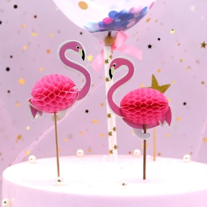 Close-up of pink honeycomb flamingo cake toppers with stars and balloon party background
