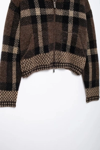 Detailed close-up of brown and black plaid fuzzy knit jacket with double zipper texture