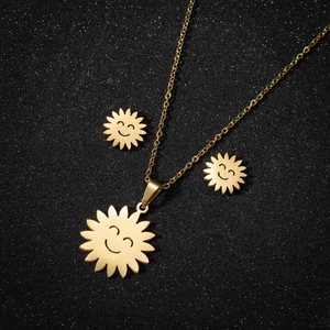 Detailed view of gold sun face necklace and earrings set on shimmering black background