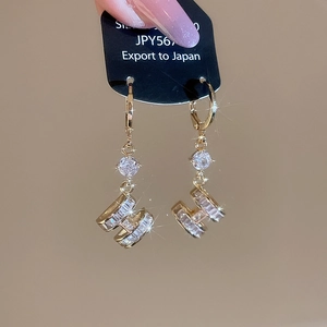 Macro detail of 14K gold plated earrings with H pendant and sparkling cubic zirconia crystals