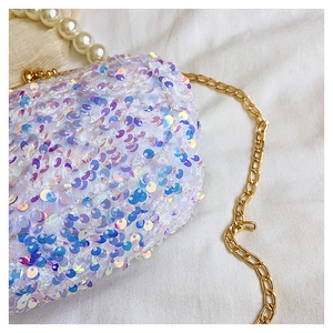 Close-up of white iridescent sequins, gold chain strap, and pearl handle on evening bag