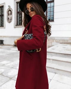 Detail shot of a dark red wool blend long coat for women worn in a street setting