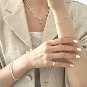 Close-up of 925 sterling silver irregular ring and layered jewelry set on a model