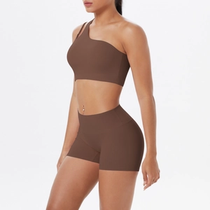 Detail eines schokoladenbraunen Yoga-Sets mit One-Shoulder-Top und Shorts am Modell