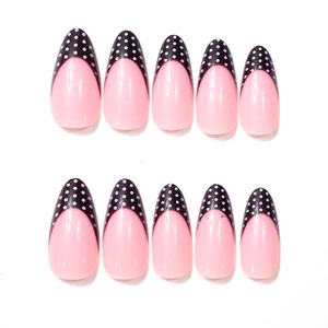 Detail of almond-shaped false nails with pink base and black polka dot french tips