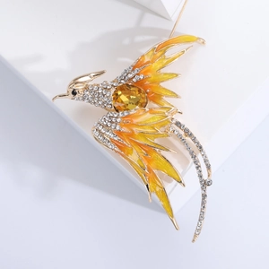 Macro shot of elegant phoenix brooch with yellow crystals and orange enamel detailing