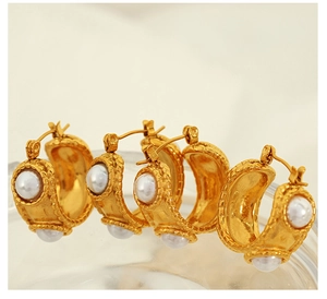 Macro view of C-shaped 18k gold plated stainless steel earrings with white pearl inlay