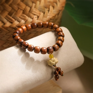 Macro detail of dark rosewood prayer beads featuring a carved lotus and yellow tassel