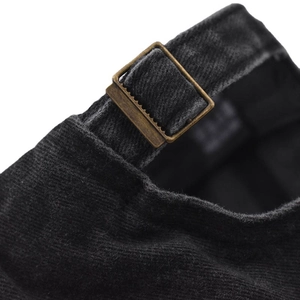 Detail of vintage copper adjustment buckle on black corduroy baseball cap with striped texture