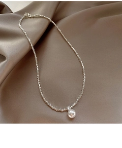Close-up of irregular silver bead necklace with a round pearl on champagne satin