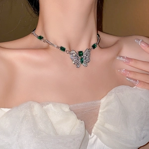 Détail du collier argenté avec pierres vertes et pendentif papillon pavé sur modèle
