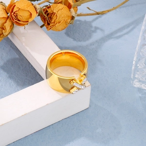 Detail of gold wide band ring with X-shape zircon inlay and elegant metallic finish