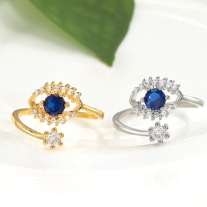Dettaglio di anelli regolabili malocchio in finitura oro e argento con zirconi blu