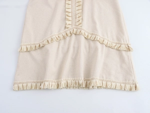 Détail d'une robe bohème beige avec des franges multicouches et un ourlet ondulé