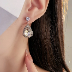 Gros plan détaillé d'une boucle d'oreille goutte en cristal avec monture halo sur modèle