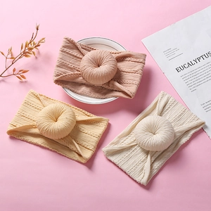 Detail of knitted baby headbands with donut knots in pink, yellow, and beige colors
