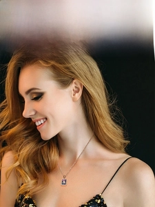 Close-up of model wearing a gold square pendant necklace with a blue letter A shell inlay