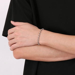 Close-up of a silver stainless steel rolo chain bracelet worn on a wrist over black clothing