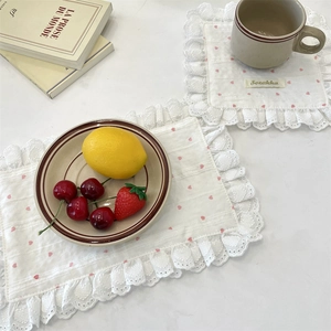 Detail of white lace placemats with pink hearts and decorative scalloped edges
