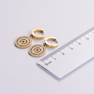 Detail view of gold roman numeral earrings with crystals next to a ruler for size