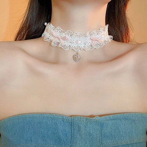 Close-up of white lace choker with pink ribbon bow and heart crystal pendant on neck