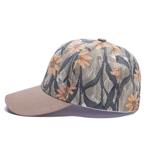 Detail view of floral print baseball cap with orange daisies and brown brim contrast