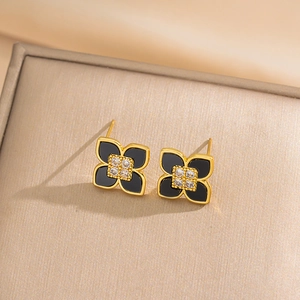 Golden clover earring set with black inlay and zircon crystal on luxury fabric