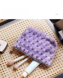 Detail of purple plush checkerboard makeup bag featuring star charm and soft texture
