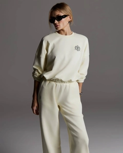 Détail de l'emblème du sweat crème et du jogging à la taille haute sur mannequin