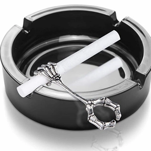 Detailed view of skull hand cigarette ring holder on a black ceramic ashtray