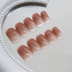 Brown gradient cat-eye press-on nails with white bow detail on pearl mirror tray