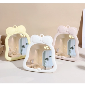 Dettaglio di specchi da trucco con fiocco nei colori giallo, bianco e rosa pastello