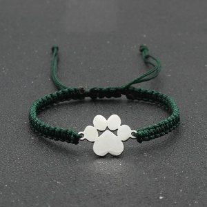 Detail view of a handmade green braided bracelet with a silver metal paw charm pendant