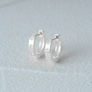 Detailed close-up of S925 sterling silver huggie hoop earrings with sparkling zircon stones