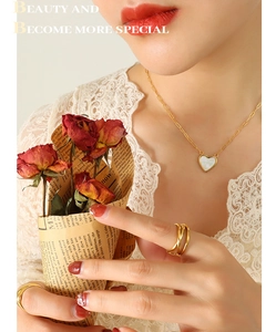 Golden heart necklace with white mother of pearl inlay worn with stacked rings