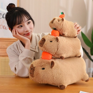 Three sizes of brown plush capybara toys with orange fruit decor on heads