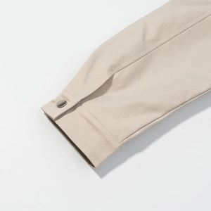 Close-up of beige jacket sleeve cuff with button detail and high-quality stitching texture