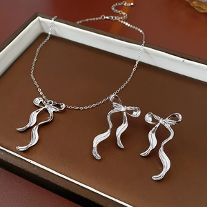 Vue détaillée d'un ensemble collier et boucles d'oreilles nœud argenté sur plateau
