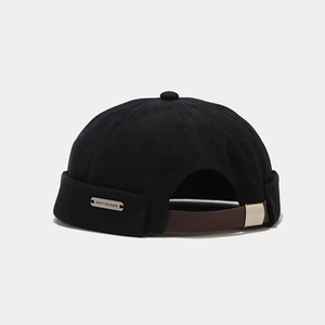 Détail du bonnet docker en coton noir avec sangle en cuir marron et plaque en métal