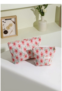 Detail of floral knit cosmetic bags showing woven texture and flower zipper pull
