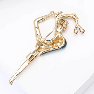 Macro detail of alloy dancing girl brooch showing back pin structure and gold finish