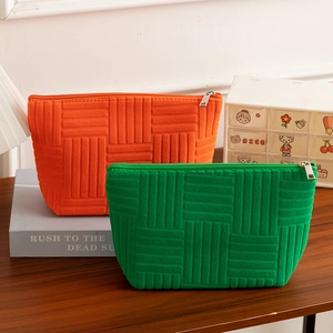 Detail of orange and green textured towel fabric makeup bags with metal zippers