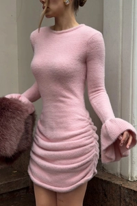 Détail de la robe en maille rose avec manches évasées et tissu froncé texturé