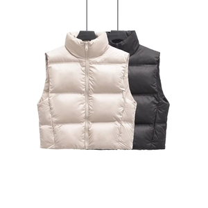 Detail view of stand-up collar and windproof fabric on puffer vests in beige and black