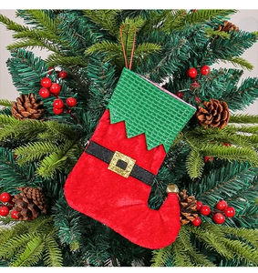 Close-up of Christmas stocking with gold buckle and bells hanging on a festive tree branch