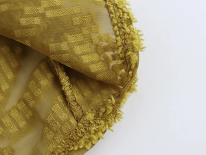 Detail view of yellow-green mesh fabric with square texture and raw fringe edges
