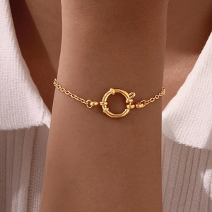 Close-up of golden flat cross chain bracelet with a large circular spring ring clasp